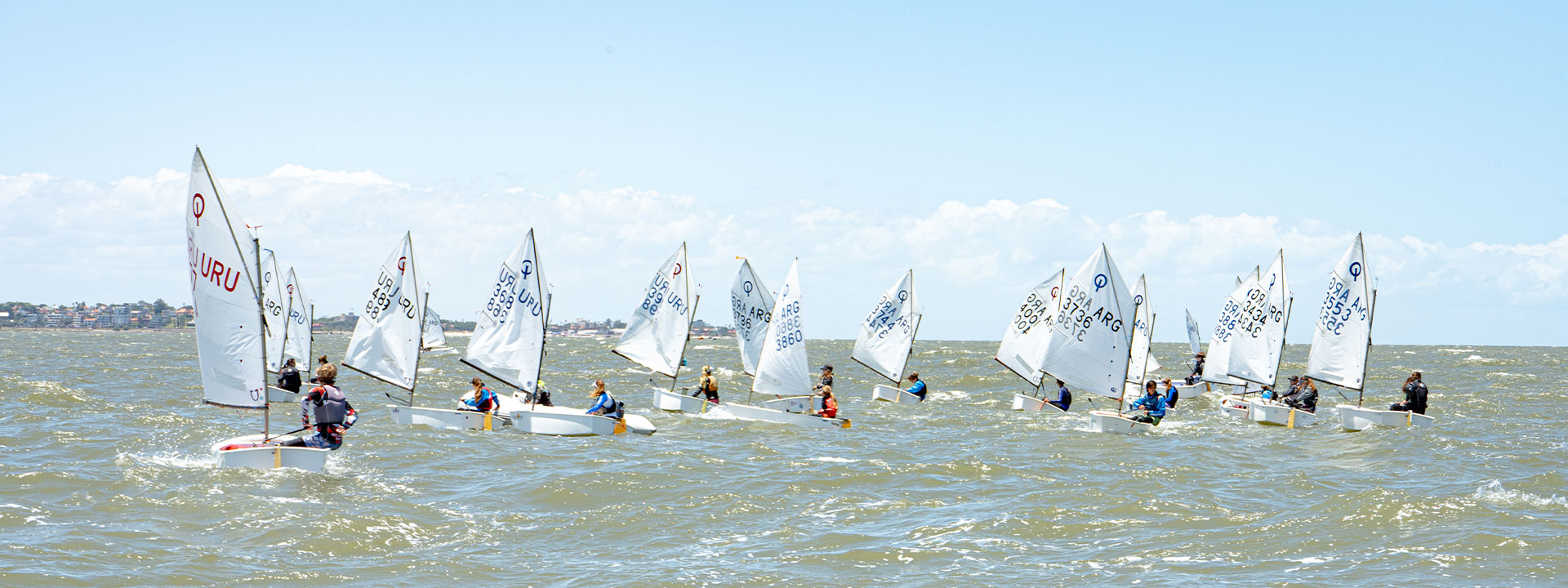 Flota de Optimist navegando en el Río de la Plata